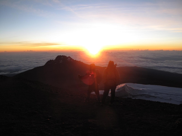 Couple watching sunrise from Uhuru Peak on Mount Kilimanjaro